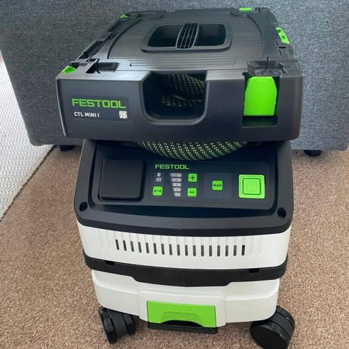 Festool CTL Mini I dust extractor with a compact design, featuring green and black accents, placed on a carpeted floor.